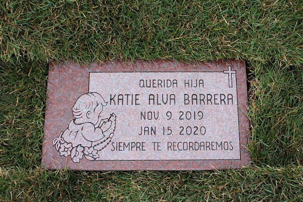 Red granite Childs marker with Spanish lettering and angel carving