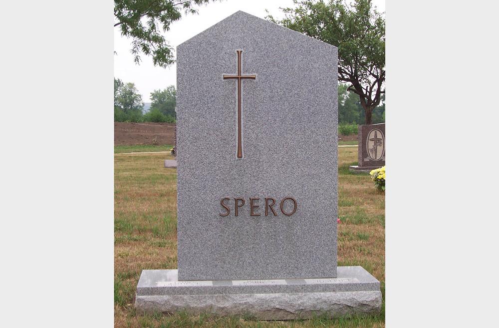 Simple grey granite family monument with bronze cross and last name