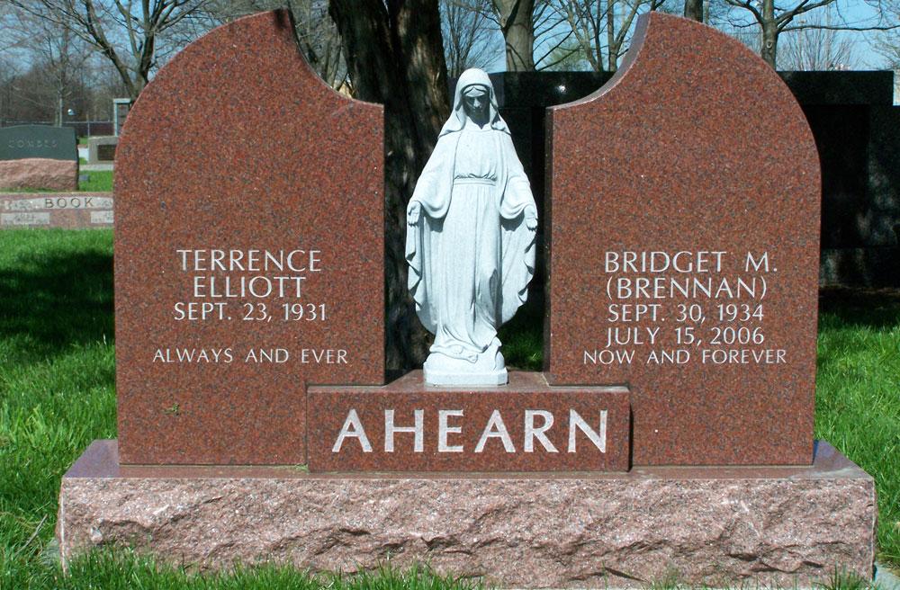 Winged two grave monument in red granite with center statue